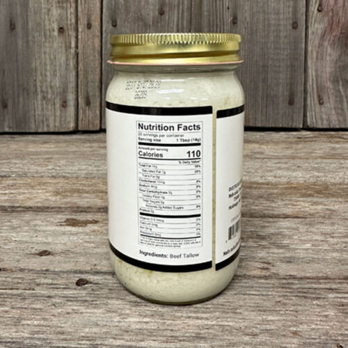 Jar of beef tallow with a Nutrition Facts label at a rustic wooden table, ingredients listed as Beef Tallow in view.